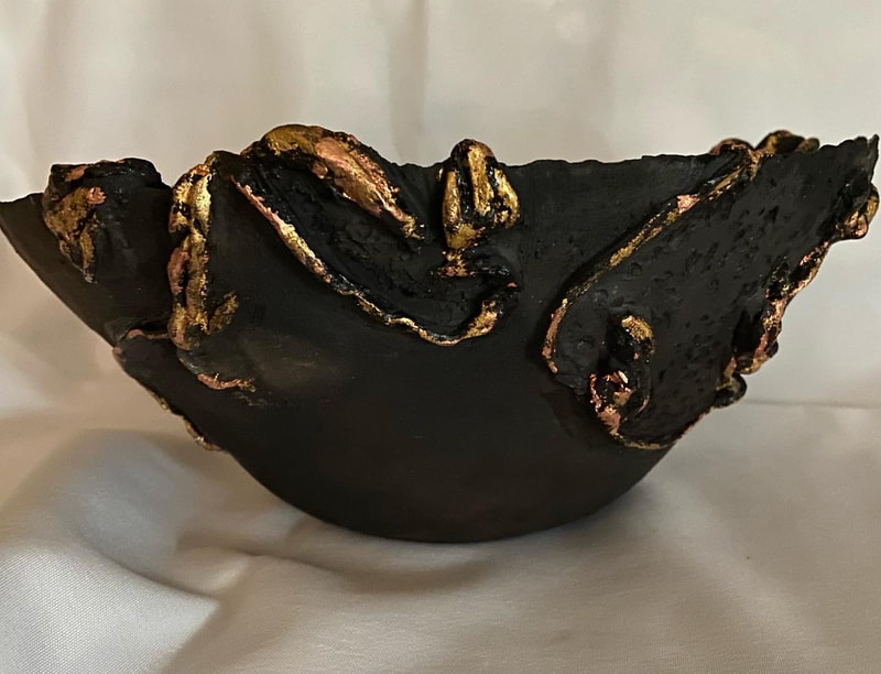This bowl has gold and copper vines weaving in and around its open, pit fired (dark, smokey) body