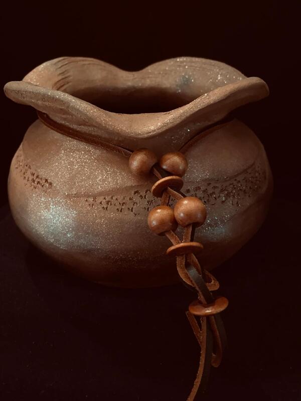 8" x 5" mica, textured and burnished pot. Pit fired with beaded leather around its neck.