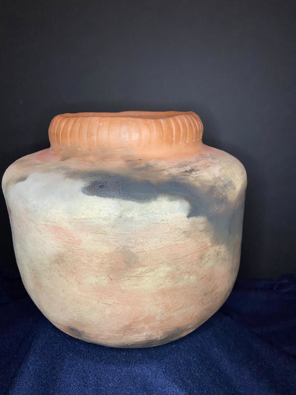 Large pot covered in an ash finish then pit fired to achieve smoky clouds around the red clay body. 
