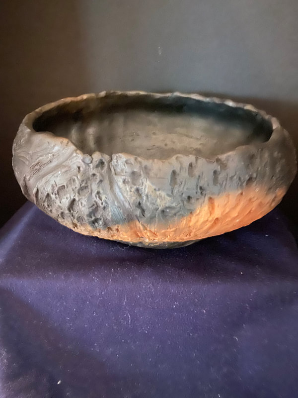 Large bowl surrounded by heavy texturing. Pit fired to bring out the natural orange clay, while surrounded by smoke rings.