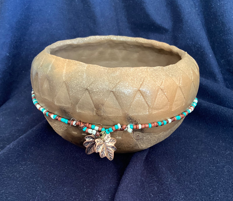 Pot made of mica clay, beaded with coral, turquoise type beading and gold/bronze leaves.